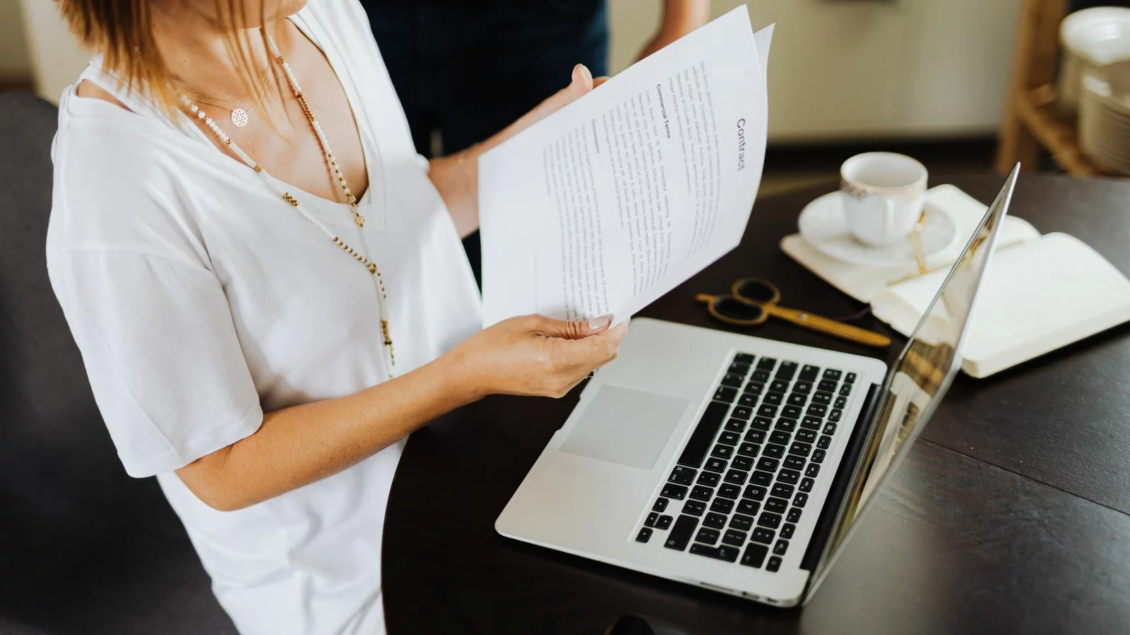A professional reviewing written role terms beside a laptop