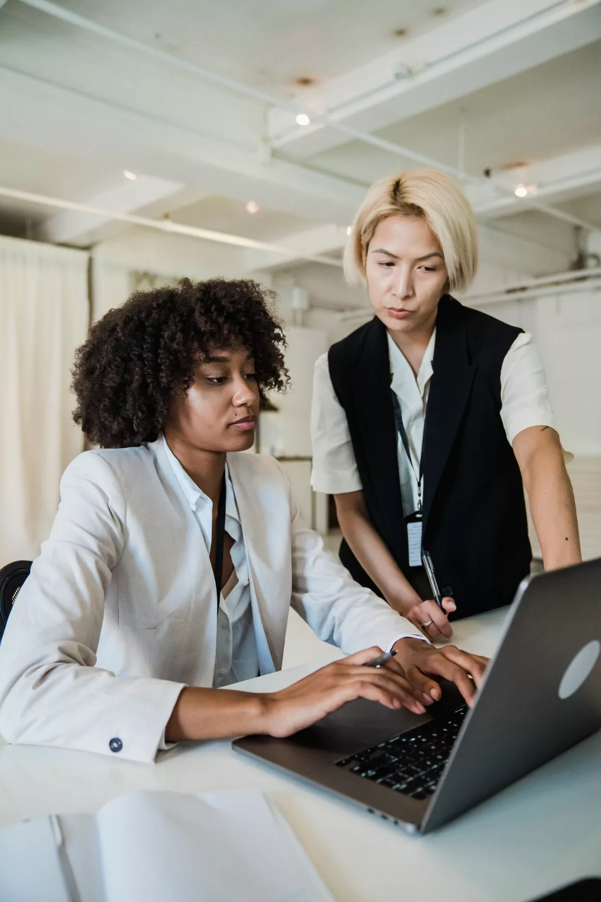 A mentor guiding a professional at a laptop